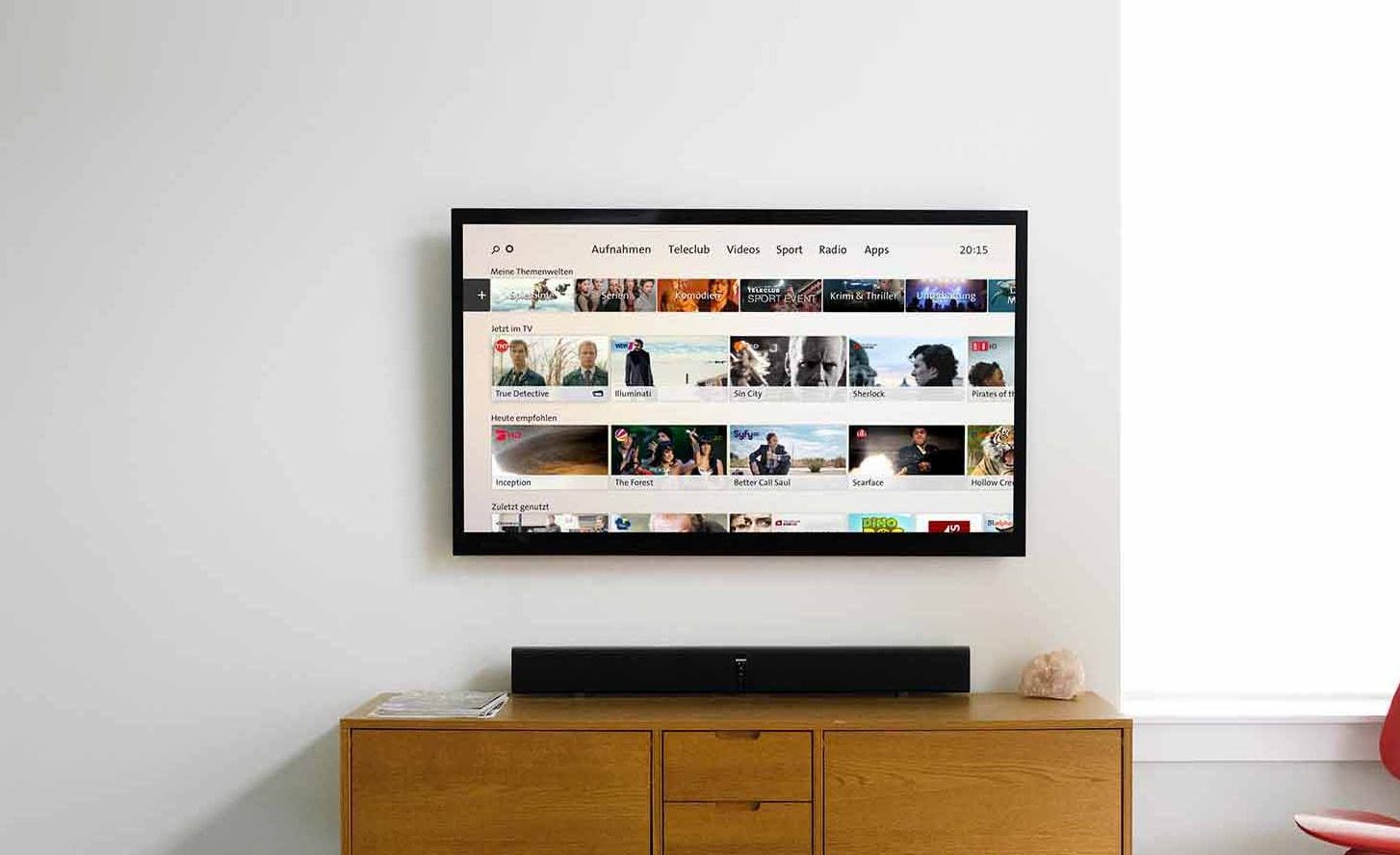 Wall-mounted TV in a living room showing the Swisscom TV interface